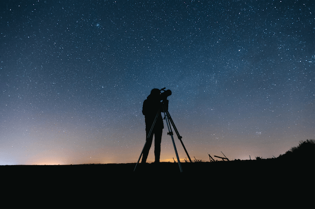 Person stargazing in Zion with a telescope under a clear night sky.