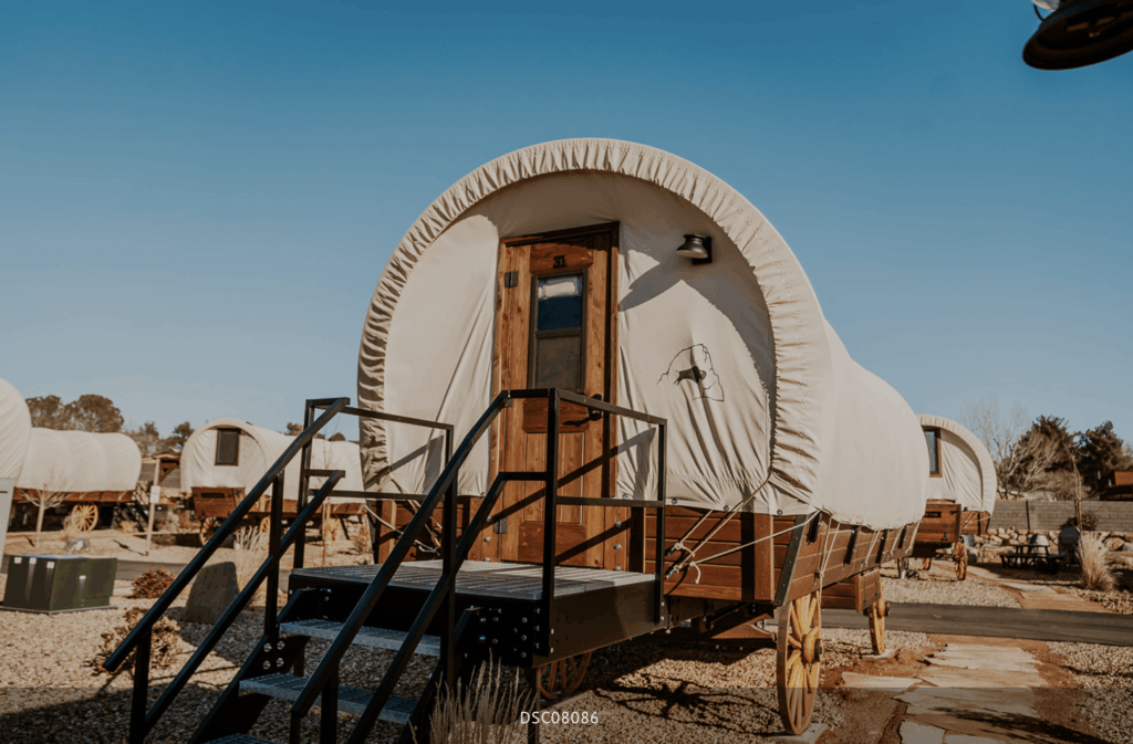 A unique glamping pod near Zion National Park, featuring a wagon-style design with a curved roof, wooden door, and steps leading to the entrance.