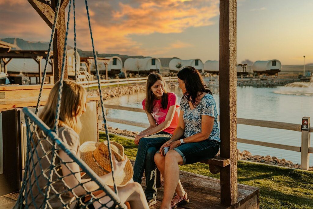 Family enjoying a relaxing outdoor moment at a glamping site with a scenic sunset view.