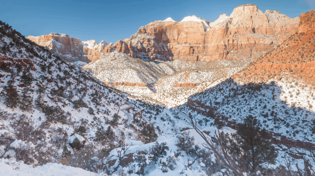 Scenic view of Zion National Park in winter with snowy landscapes and red rock formations under a clear sky.