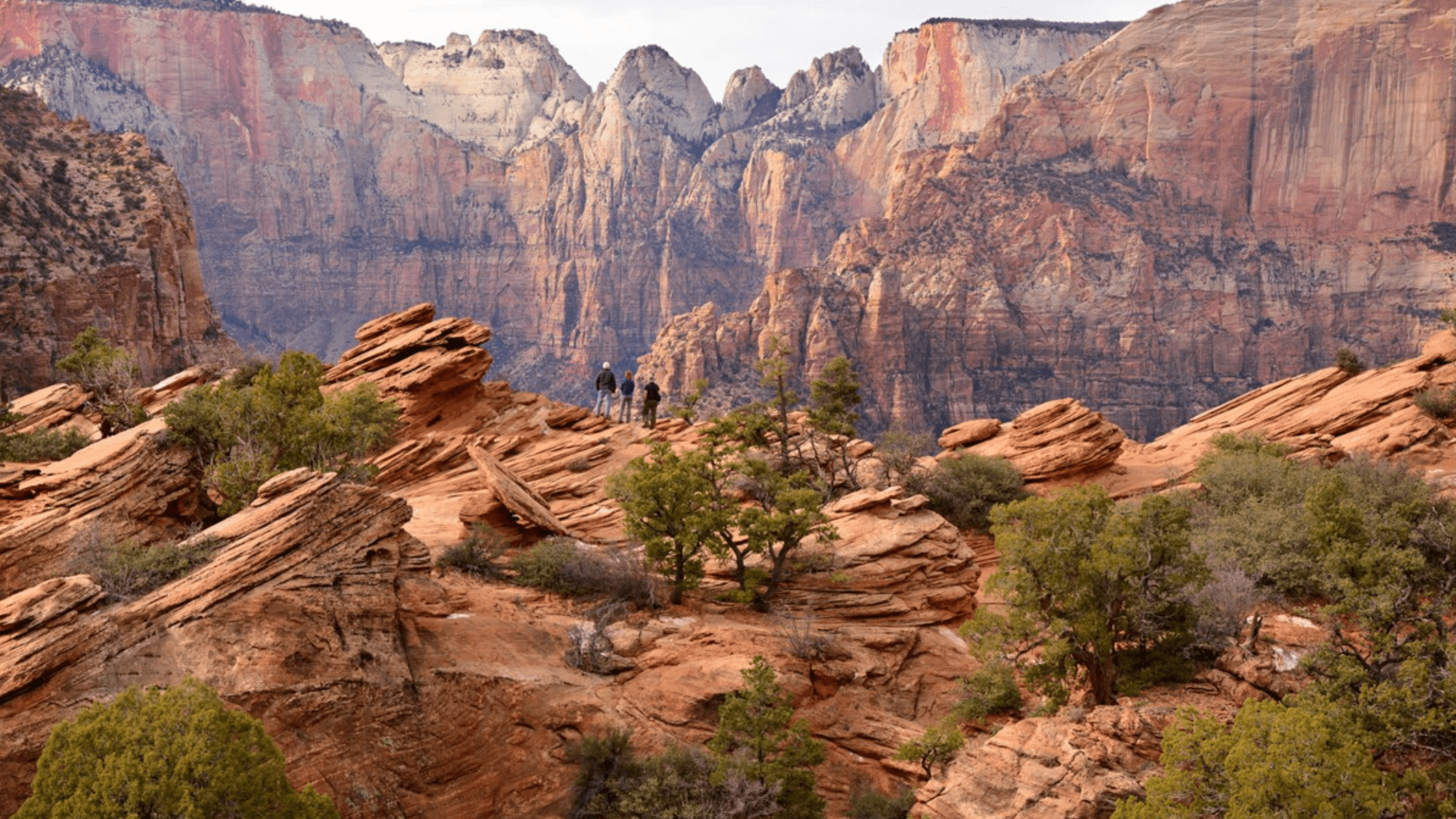 two hikers scaling the red rocks of zion national park