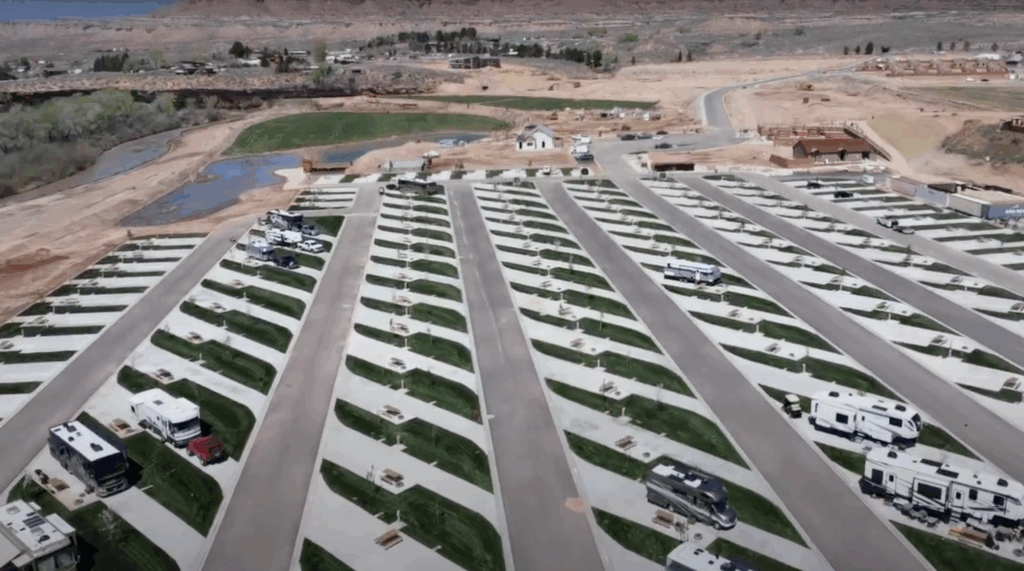 Aerial view of an RV campground with neatly organized rows of RVs parked on paved sites surrounded by green lawns.