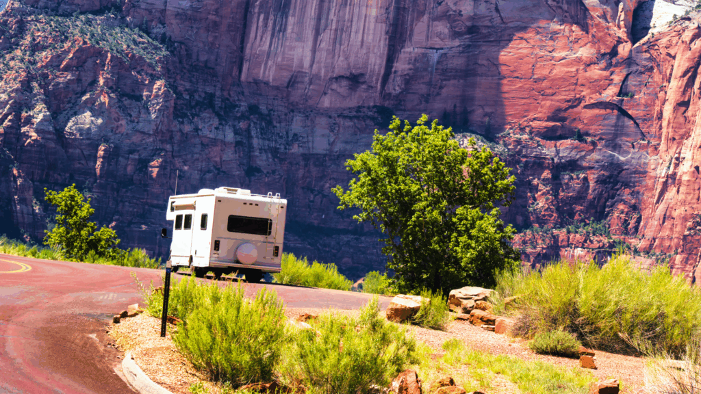 RV parked in front of sunlit rock formations of Zion National Park
