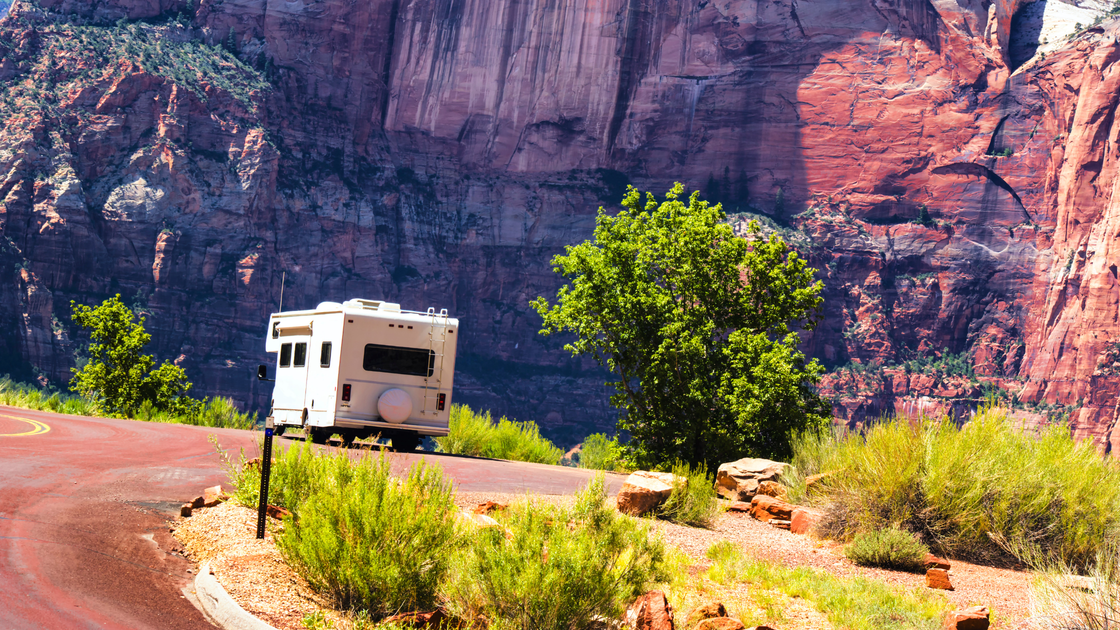 RV parked in front of sunlit rock formations of Zion National Park