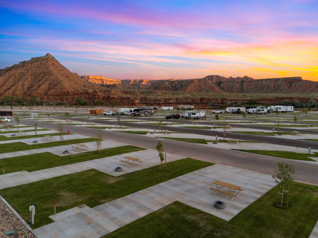 RV sites with paved roads and grassy areas at Zion White Bison Resort during sunset.